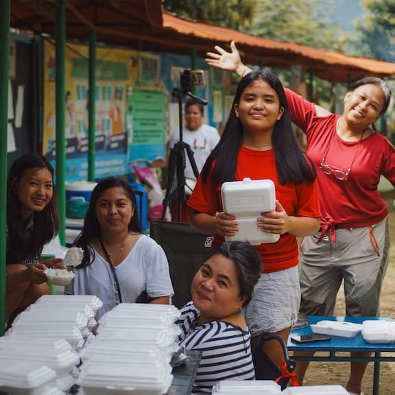 A group photo of five woman preparing foods